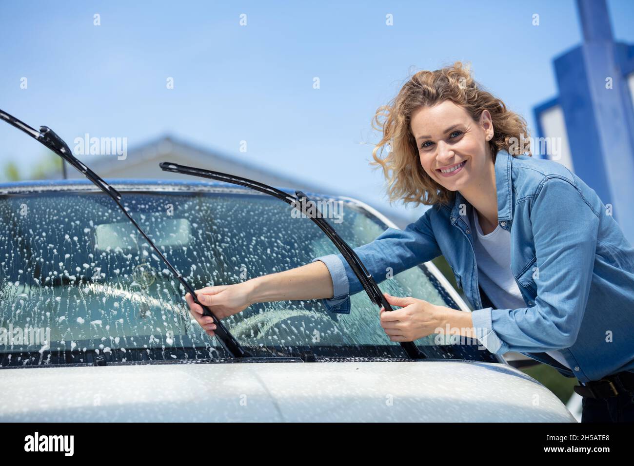 une jeune femme lave la vitre de la voiture Banque D'Images