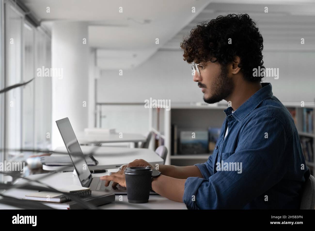Un créateur indien travaillant sur un projet utilisant un ordinateur portable dans un espace de travail commun Banque D'Images