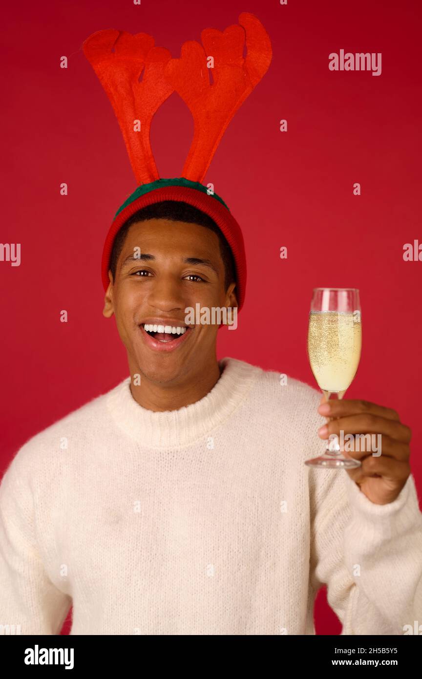 Un homme souriant en chapeau de renne avec un verre de champagne Banque D'Images