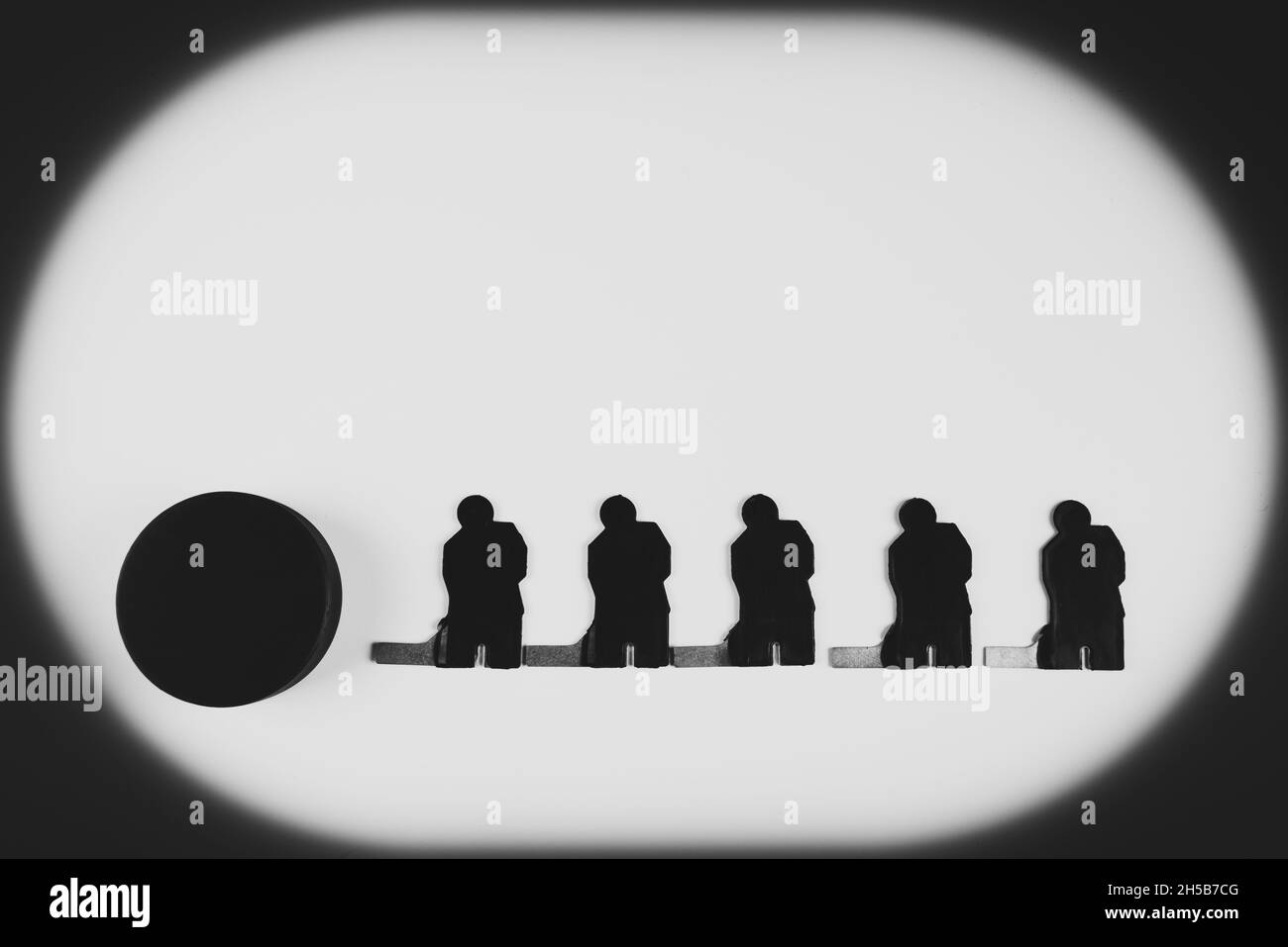 Silhouettes de cinq joueurs de hockey sur glace et d'un palet sur fond blanc. Banque D'Images