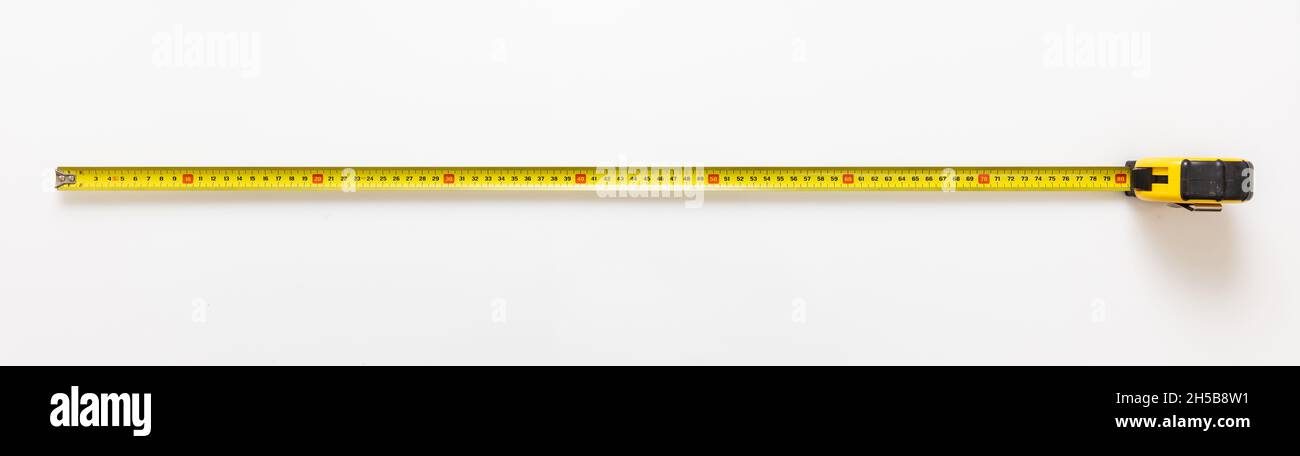 Mesurer le ruban isolé sur fond blanc.Mètre en métal de couleur jaune, outil manuel de construction, vue du dessus, bannière. Banque D'Images