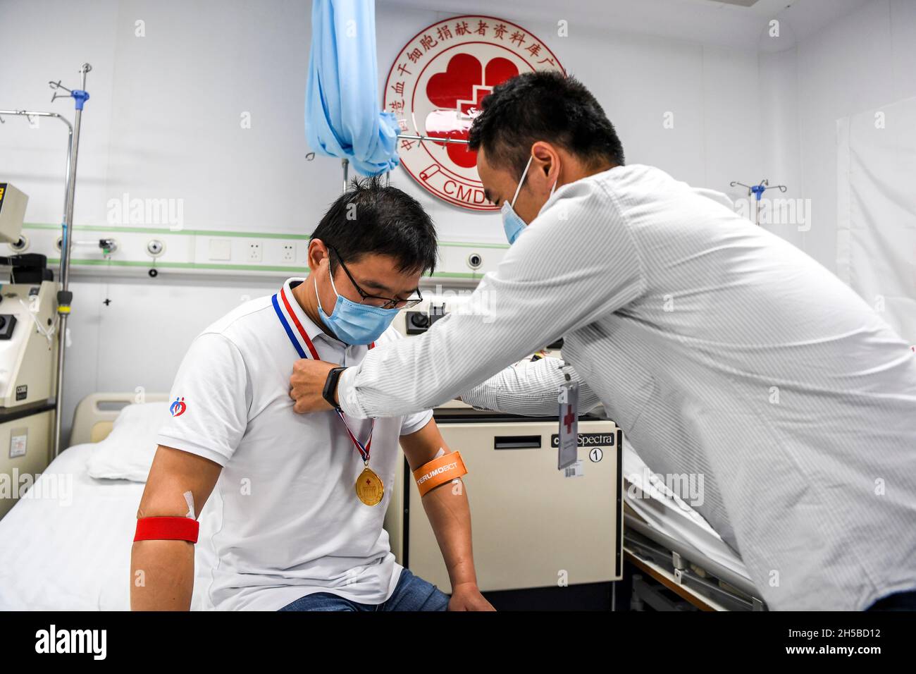 (211108) -- NANNING, 8 novembre 2021 (Xinhua) -- Un membre du personnel remet une médaille au docteur Li à l'hôpital affilié de la première université médicale de Guangxi à Nanning, dans la région autonome de Guangxi Zhuang, dans le sud de la Chine, en novembre 2021.Li, un médecin du département d'hématologie du premier hôpital affilié de l'Université médicale de Guangxi, s'est inscrit auprès du Programme des donneurs de moelle de Chine (PDMC) en tant que donneurs potentiels de cellules souches hématopoïétiques (HSC) en novembre 2011.En tant que médecin traitant des cellules souches hématopoïétiques pour les patients, il a réussi à faire correspondre un patient en tant que donneur HSC en août 20 Banque D'Images