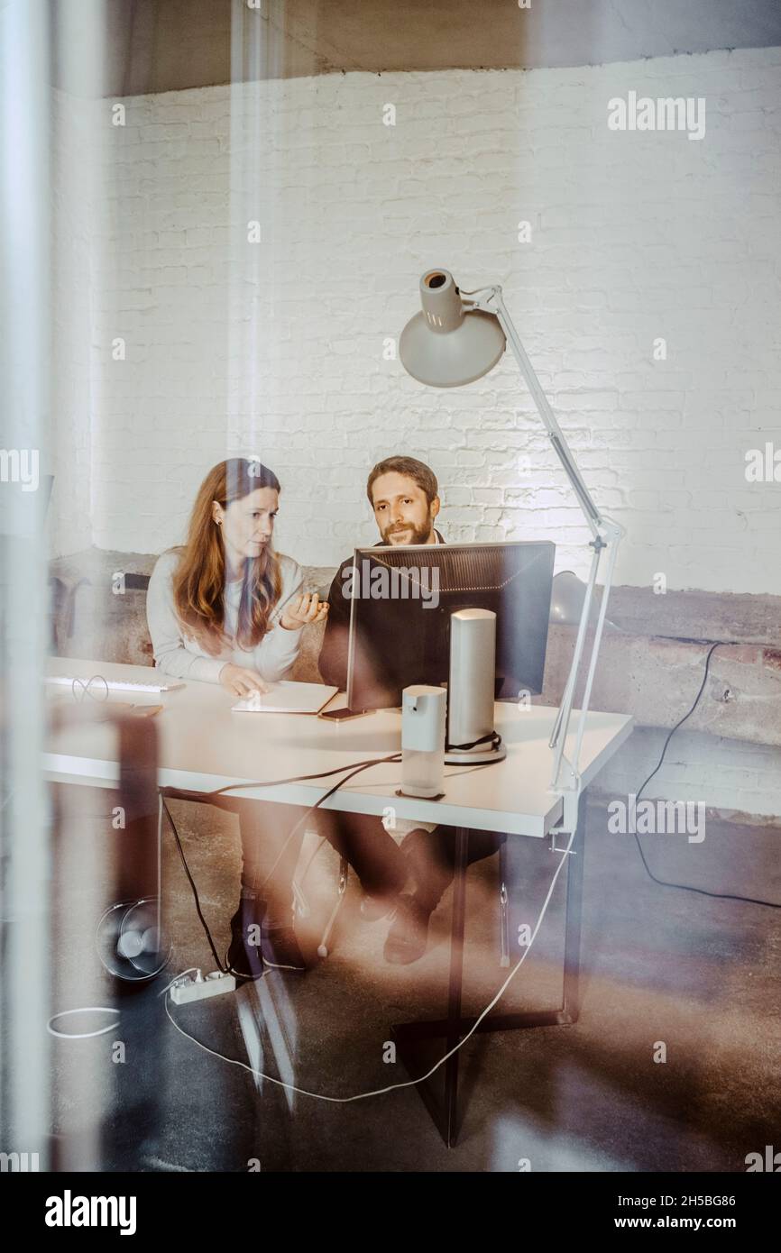 Les femmes et les hommes professionnels discutent sur ordinateur au bureau Banque D'Images