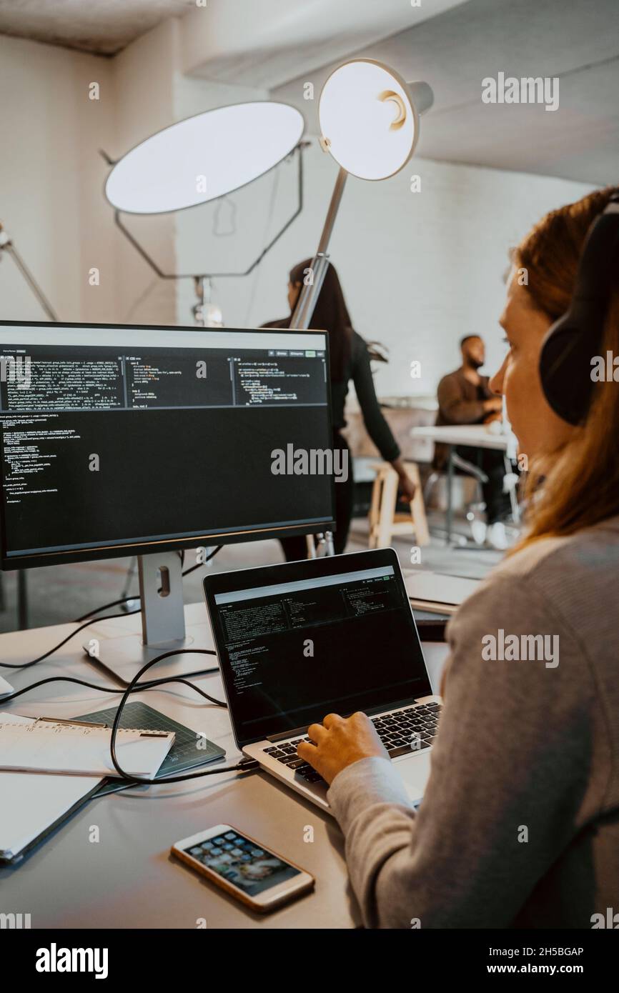 Hacker jeune femme effectuant le codage sur ordinateur dans le bureau Banque D'Images