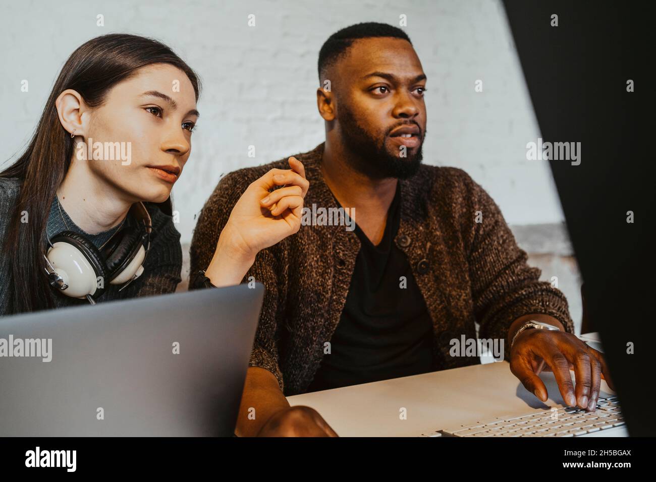 Des pirates informatiques de sexe masculin et féminin travaillant sur un ordinateur au sein d'une entreprise en démarrage Banque D'Images