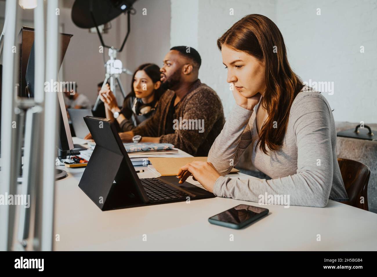 Des pirates informatiques de sexe masculin et féminin travaillant sur un ordinateur portable à la table dans une entreprise en démarrage Banque D'Images