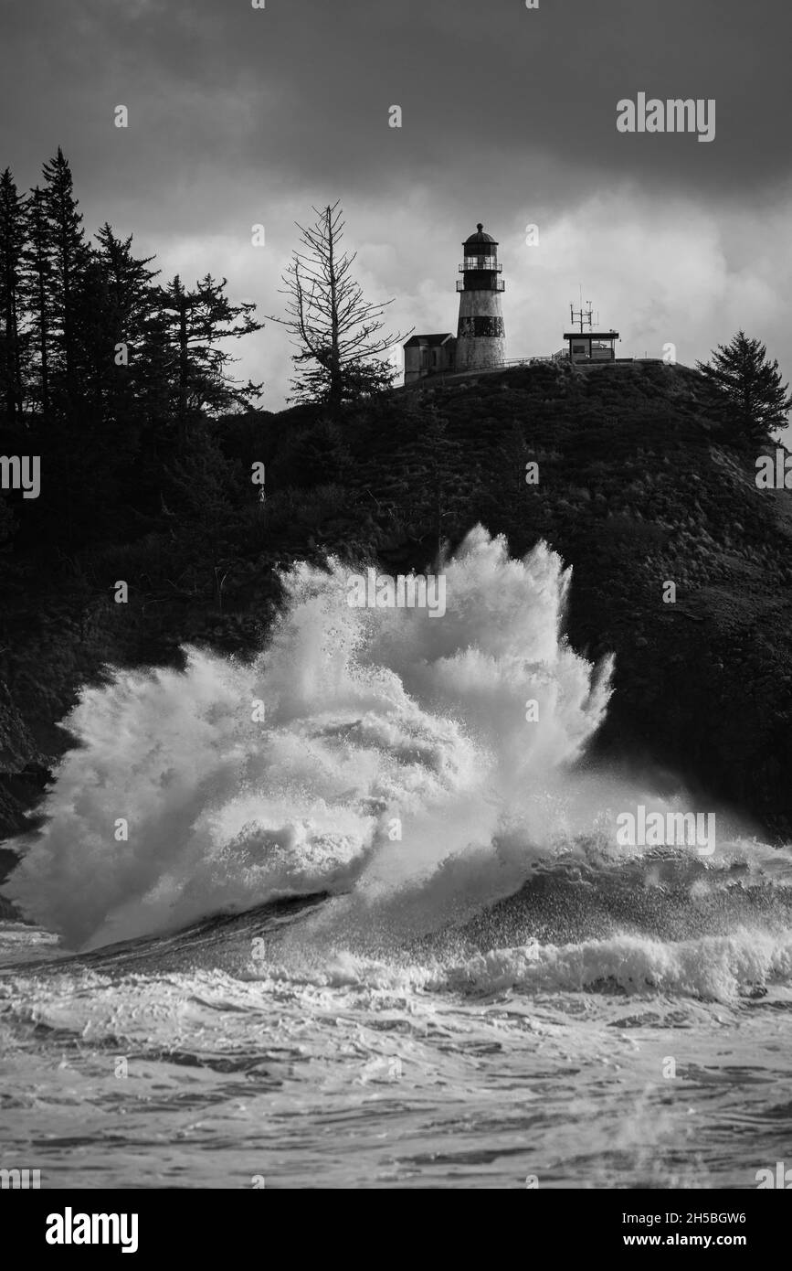 Énorme vague de choc sous la maison de lumière pendant la tempête de marée noire sur la côte du Nord-Ouest du Pacifique en noir et blanc monochrome Banque D'Images