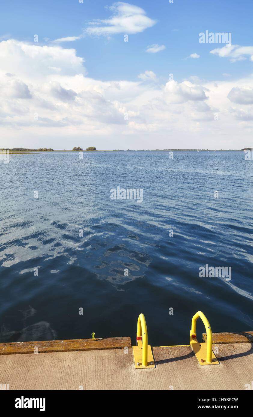 Jetée au bord du lac avec échelle jaune par beau temps. Banque D'Images Jetée au bord du lac avec échelle jaune par beau temps. Banque D'Images