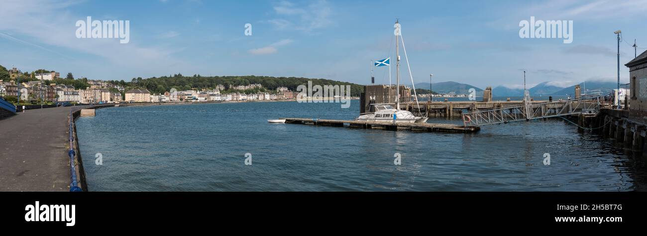 Esplanade Rothesay avec maisons en front de mer, eau libre, port et péninsule de Cowal en arrière-plan sous ciel bleu et nuage clair. Banque D'Images