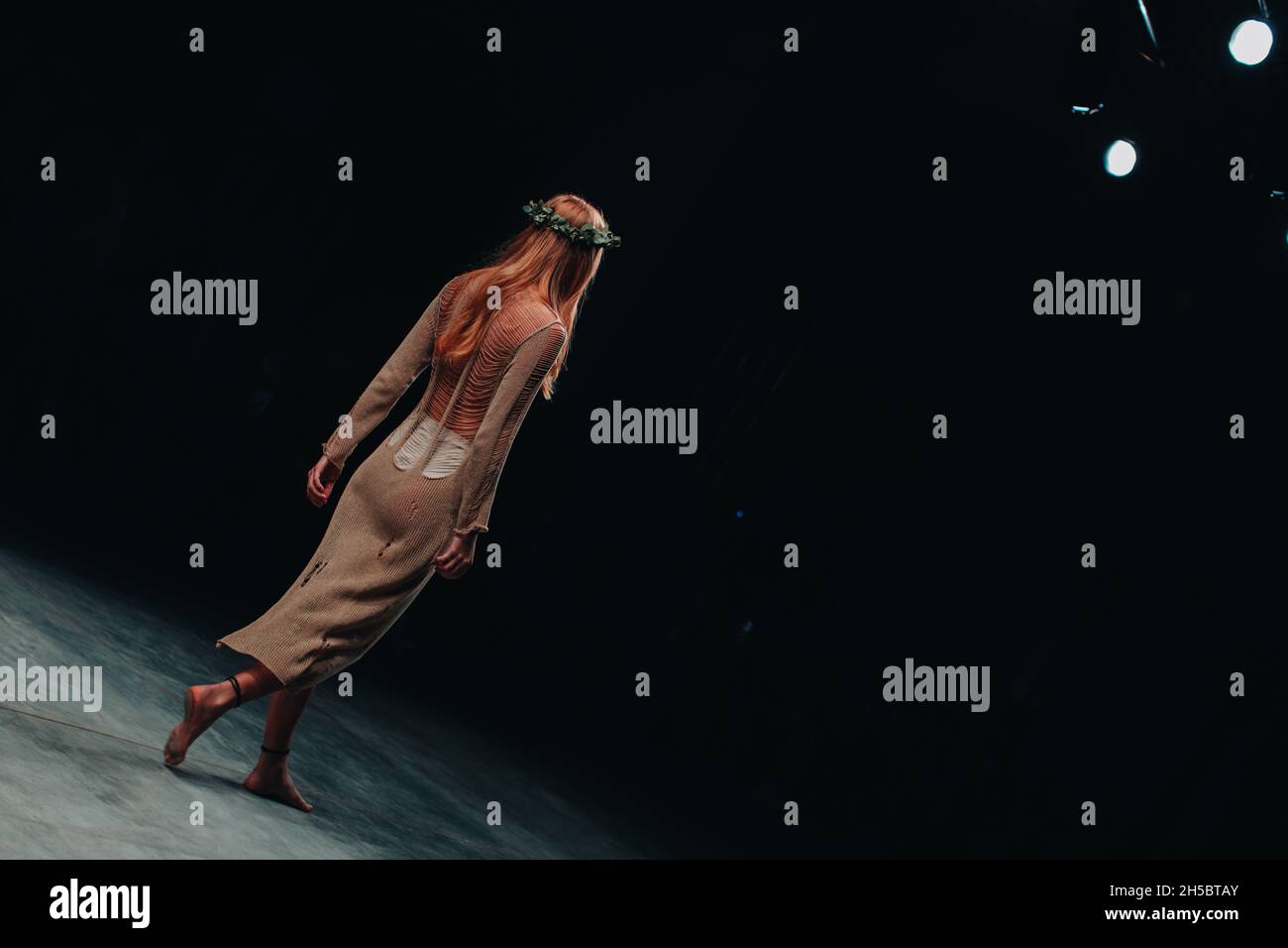 Modèle de mode n designer élégant robe longue tricotée beige marchant sur la piste d'un défilé de mode Banque D'Images