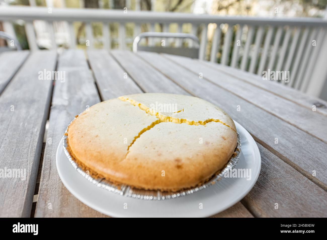 Gâteau au fromage plat entier maison cheesecake sur plaque à l'extérieur de la table en bois fond avec fissures craquelées échec de cuisson en raison de la température Banque D'Images