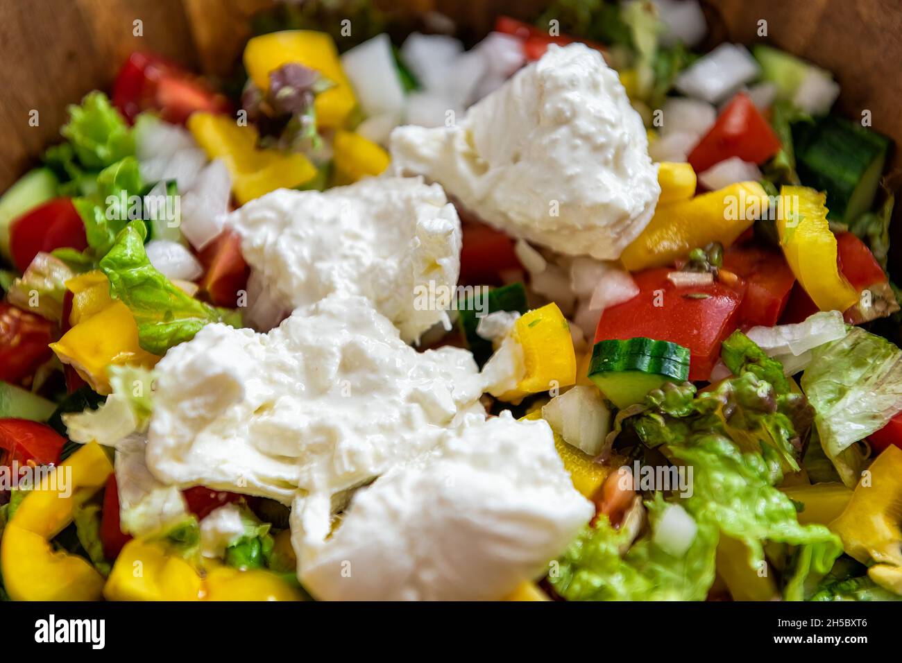 Macro-gros plan de salade fraîche avec poivrons jaunes, tomates et fromage italien burrata mozzarella émietté crémeux à l'intérieur Banque D'Images