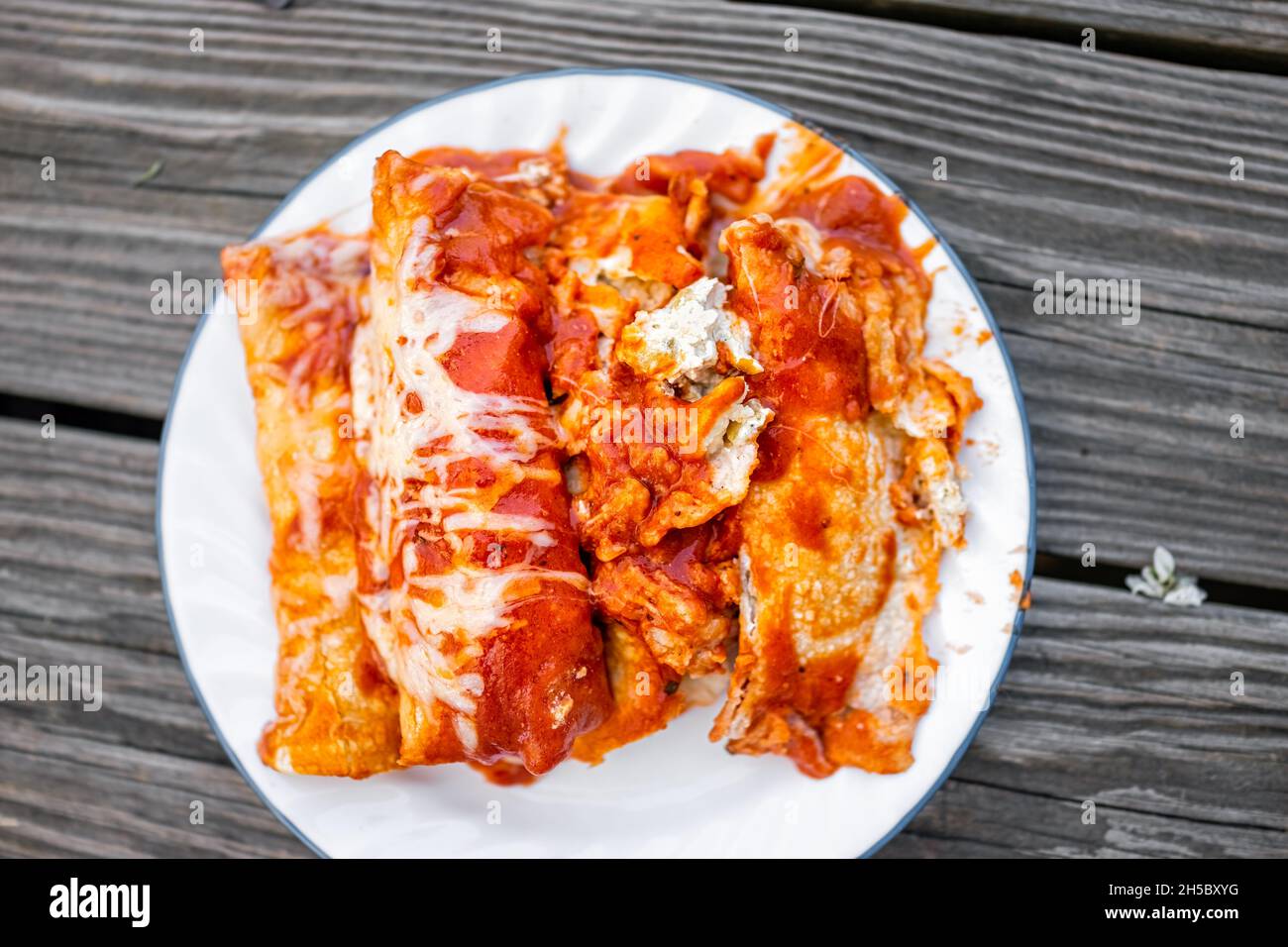 Plat au-dessus de la vue de l'assiette avec pile de nourriture mexicaine maison enchiladas avec sauce tomate, tortilla et fromage fondu Banque D'Images