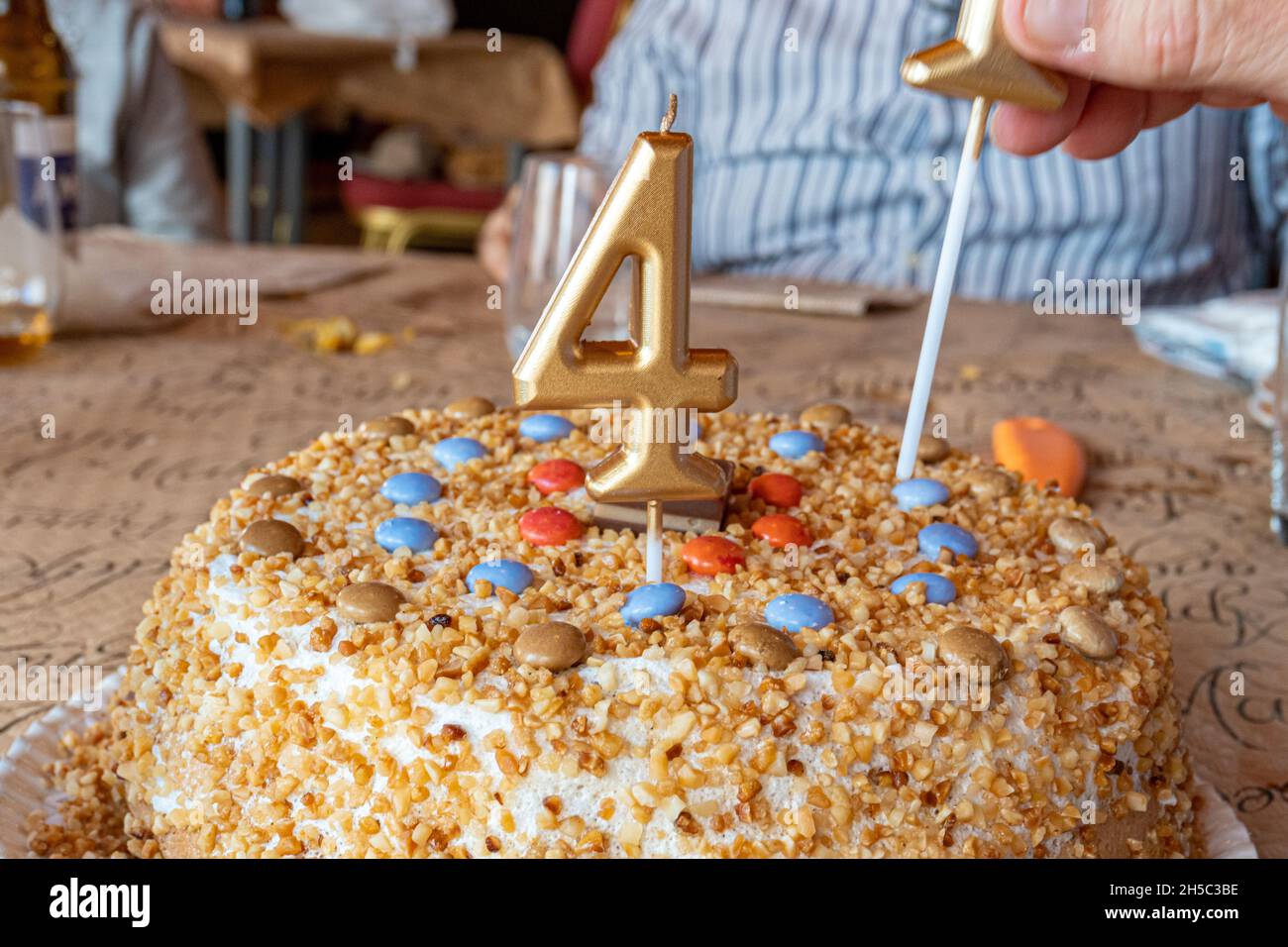 Gros plan d'une main plaçant des bougies en forme de numéro sur un gâteau d'anniversaire Banque D'Images