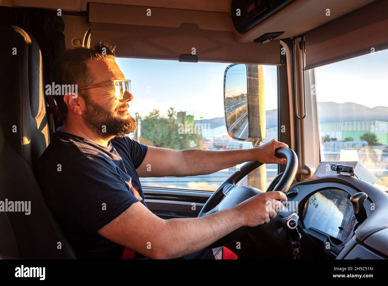Conducteur de camion lourd heureux de pouvoir conduire un camion, et de faire le geste d'OK, avec le pouce vers le haut. Banque D'Images