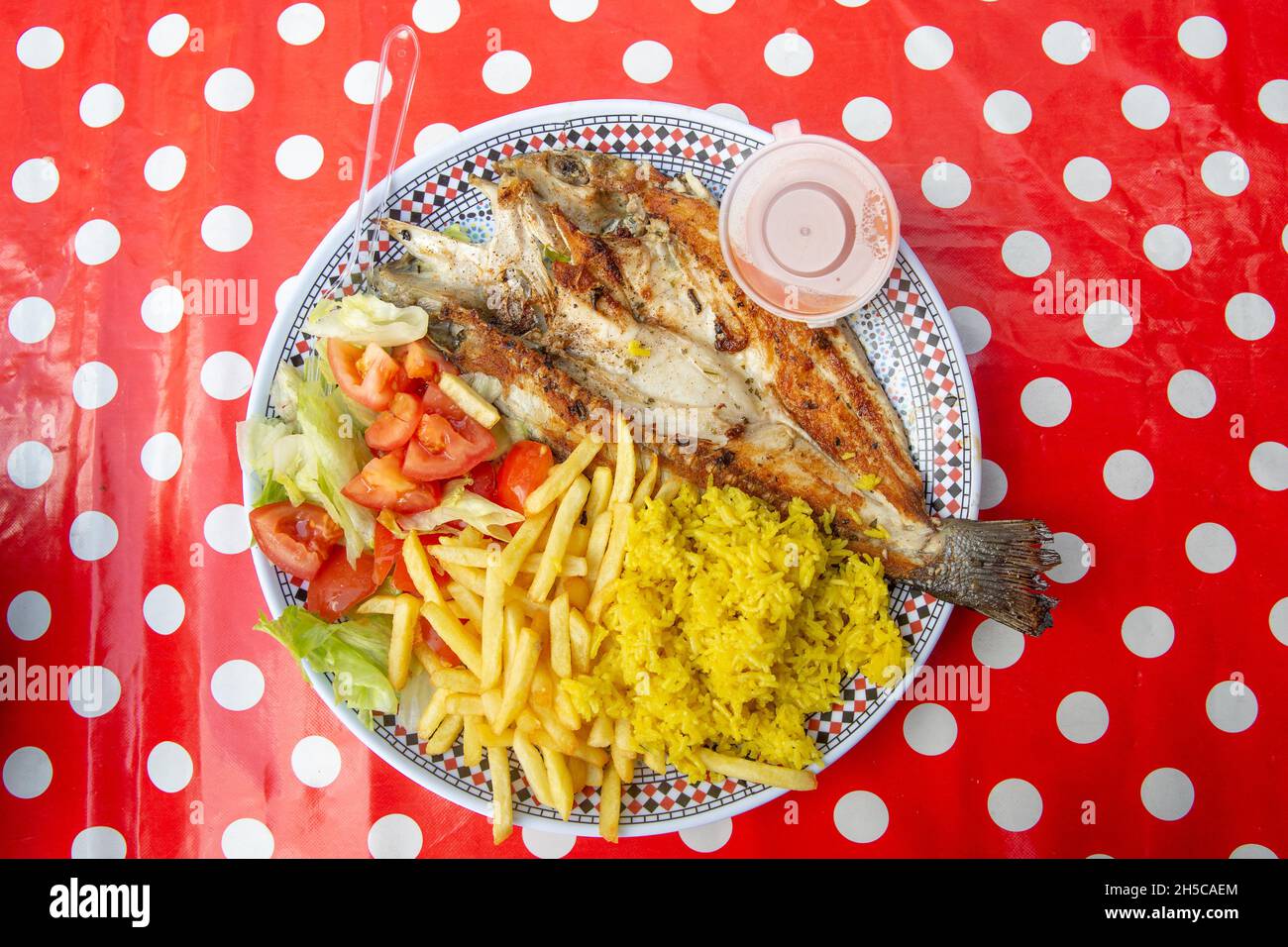 Une assiette de poisson grillé et de croustilles sur une nappe rouge vif et blanche sur Golborne Road, dans l'ouest de Londres, en Angleterre.Photo: NOUVELLES SMP Banque D'Images