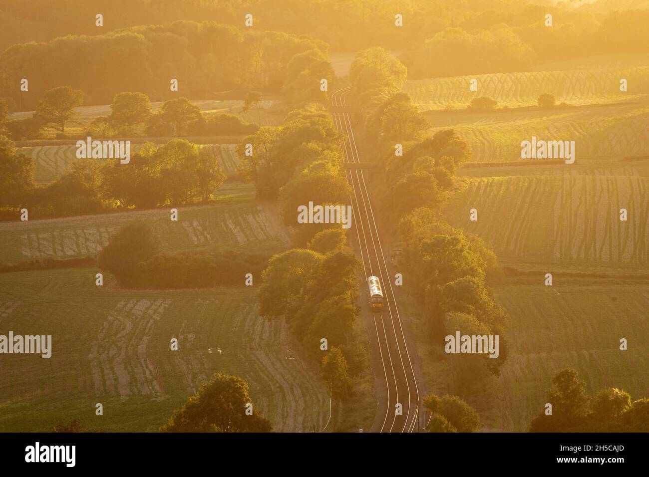 Train traversant la campagne anglaise, Surrey, lumière du soir, point de vue élevé, North Downs Line.Lumière du soleil sur les rails Banque D'Images