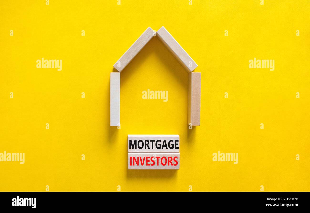 Symbole des investisseurs hypothécaires.Mots-clés 'Mortgage Investors' sur des blocs de bois près de la maison en bois miniature.Magnifique fond jaune.Affaires, plus Banque D'Images