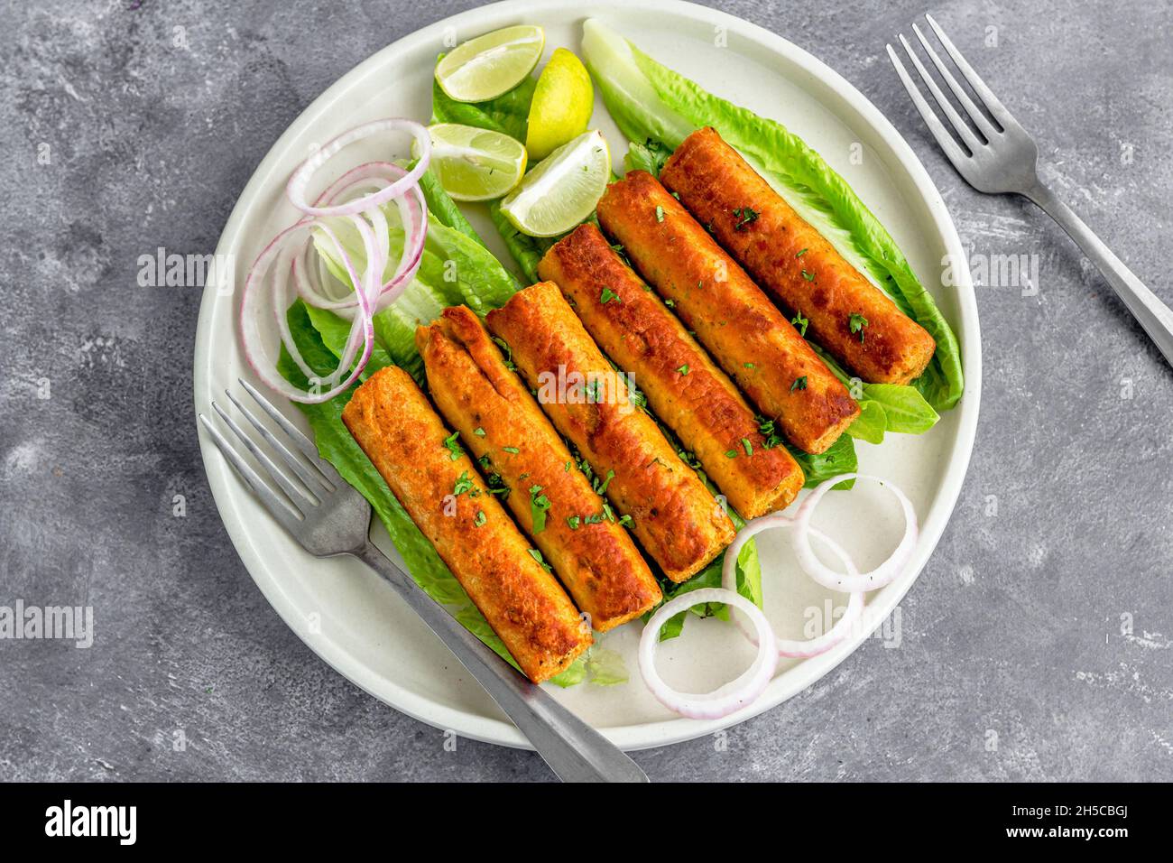 Poulet indien Seekh Kebab avec condiments sur fond sombre directement au-dessus de la photo Banque D'Images