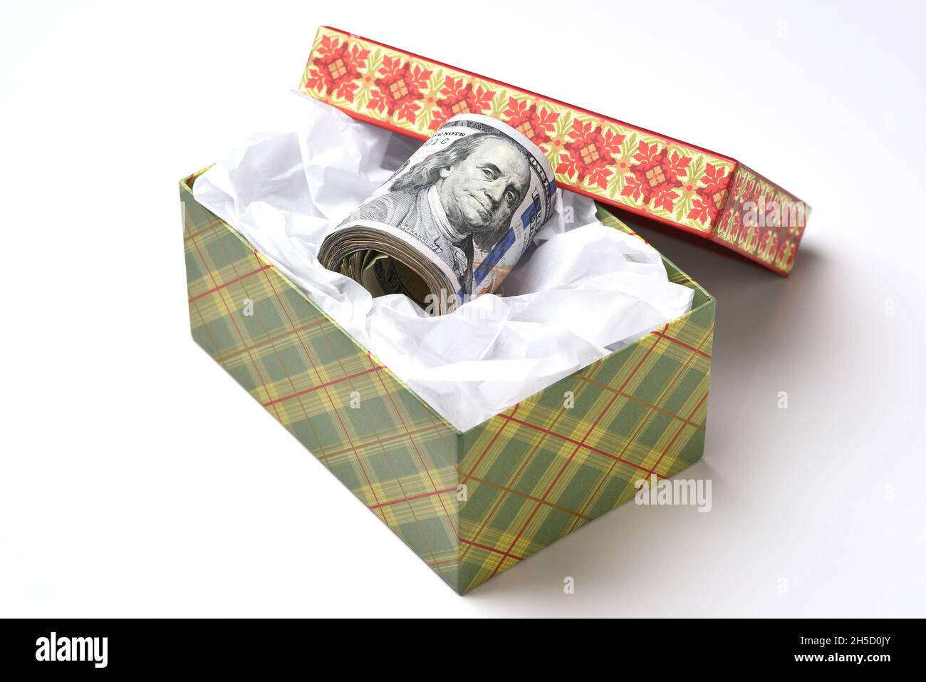 Une boîte cadeau sur le thème des fêtes avec un rouleau de billets de cent dollars. Banque D'Images