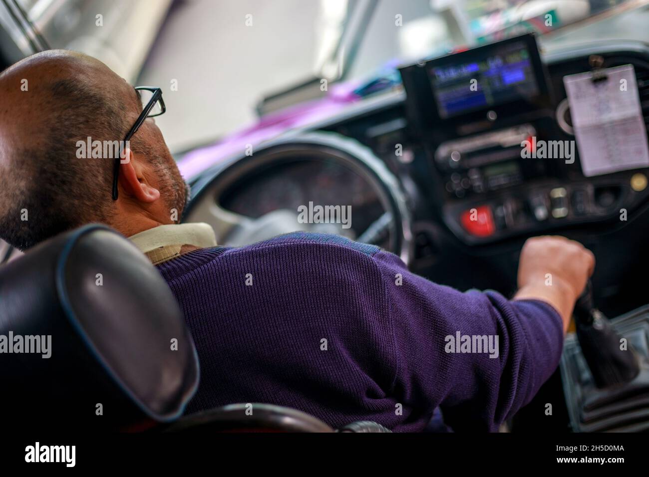 Un homme blanc conduit un bus par beau temps Banque D'Images