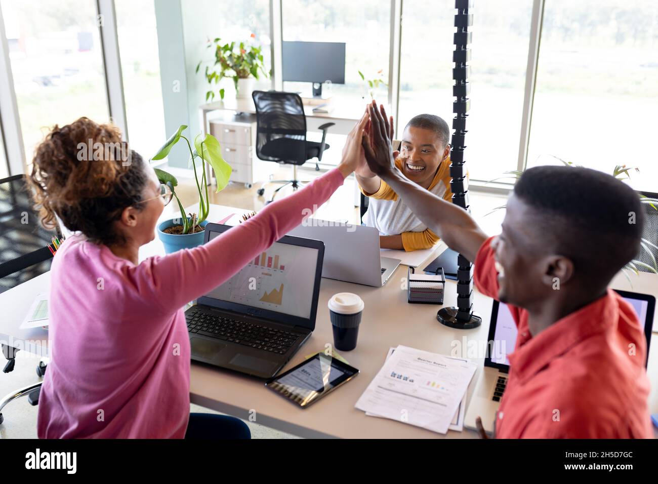 Des collègues d'affaires multiraciaux joyeux qui donnent cinq personnes à leur bureau dans un bureau créatif Banque D'Images