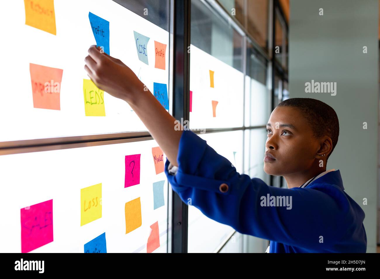 Femme d'affaires créative afro-américaine dans la planification de la stratégie des occasionnels au-dessus des notes adhésives au bureau Banque D'Images