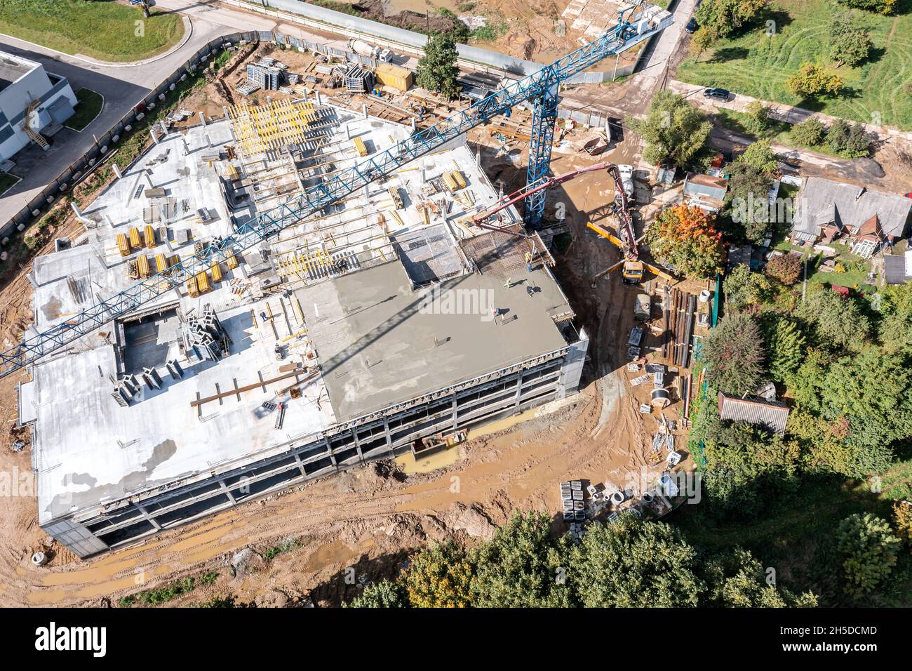 les constructeurs versant du béton humide, en utilisant le tuyau de la machine de pompage du béton sous forme de dalle de plancher. vue aérienne du chantier de construction. Banque D'Images