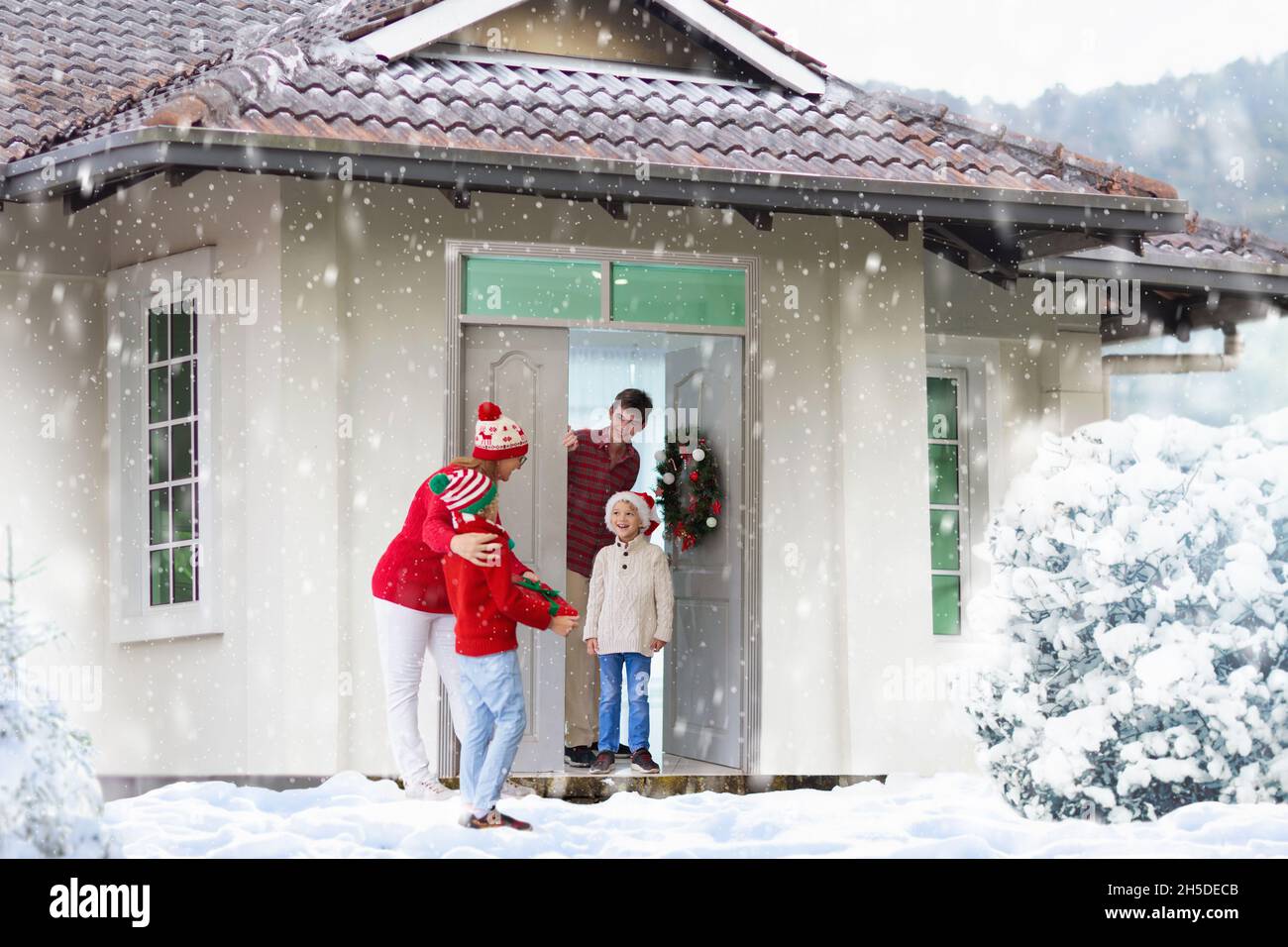 Famille visitant la grand-mère le jour de Noël. Enfants avec cadeaux à la porte d'entrée de la maison. Fête de Noël avec les grands-parents. Enfant avec cadeaux à la maison Banque D'Images