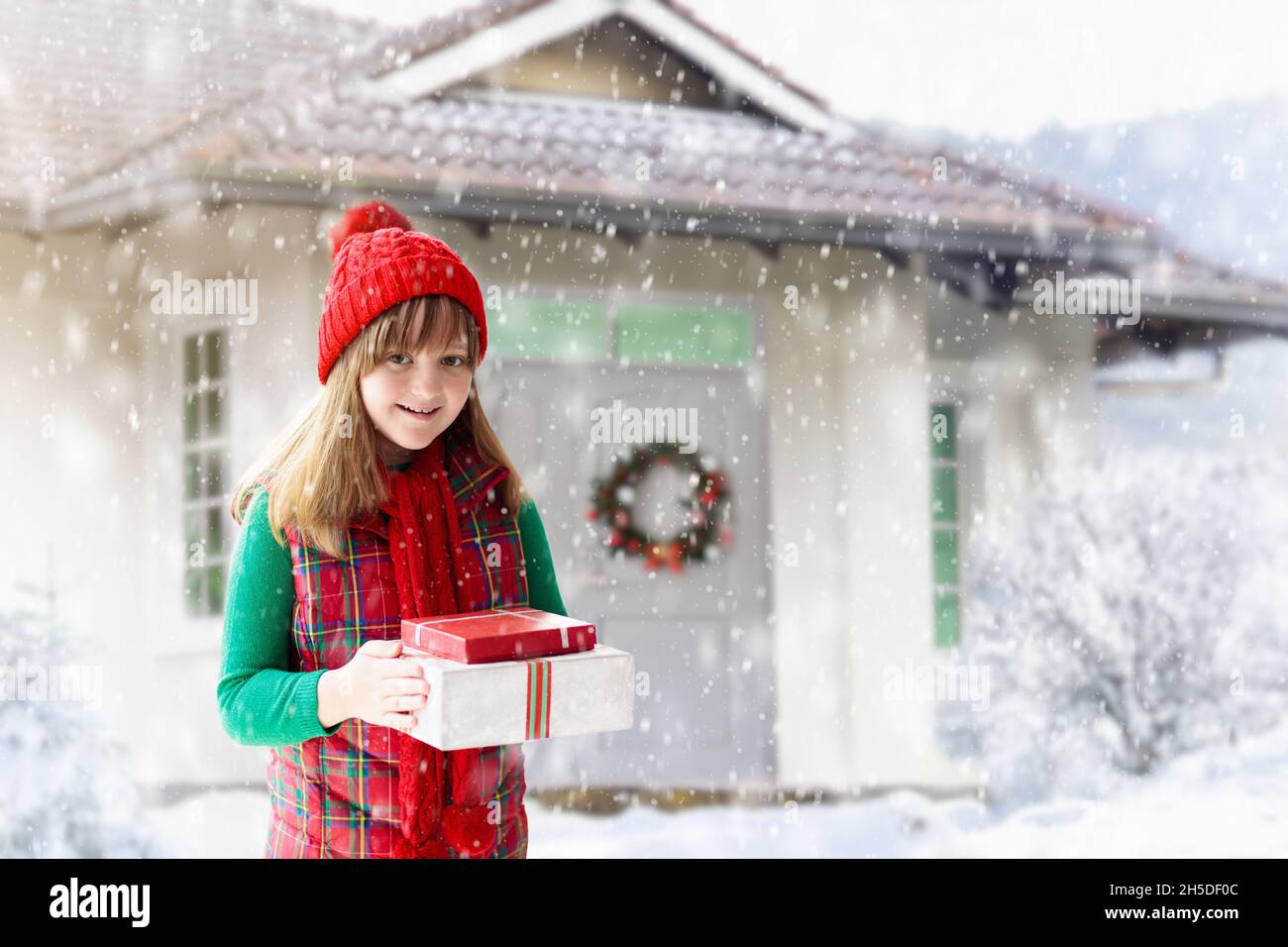 Enfant dans un chapeau rouge jouant dans la neige pendant les vacances de Noël.Cadeau de Noël en famille.En hiver, en plein air.Les enfants jouent dans un parc enneigé. Banque D'Images