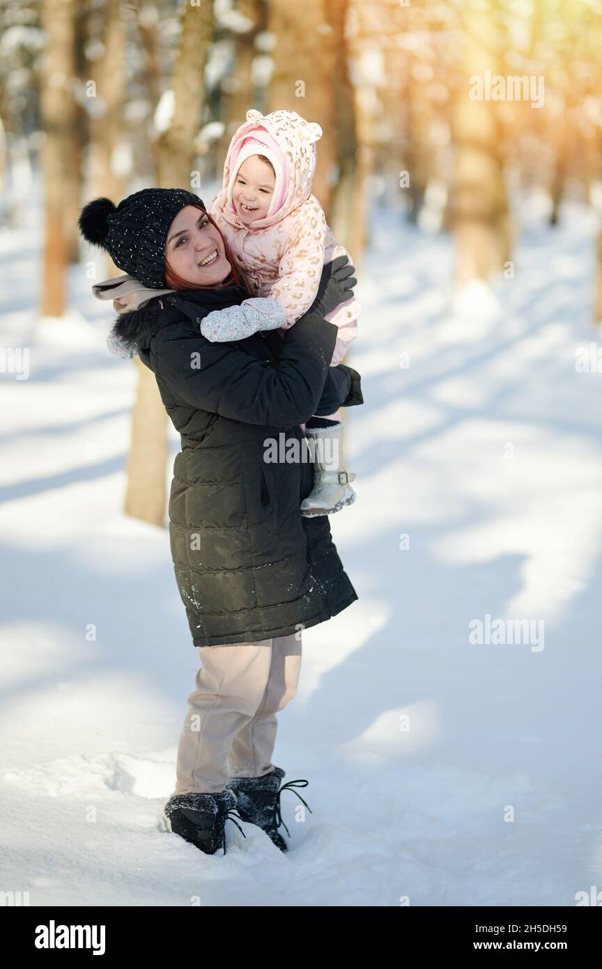 Portrait d'une maman souriante heureuse avec un enfant sur fond de parc d'hiver Banque D'Images