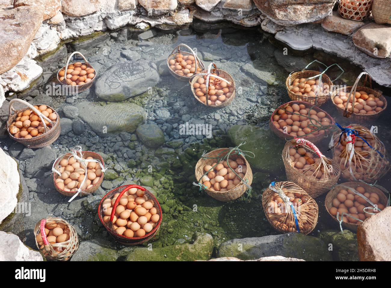 Grands paniers d'œufs cuits sous l'eau bouillante de l'étang d'eau minérale chaude à la source chaude. Banque D'Images
