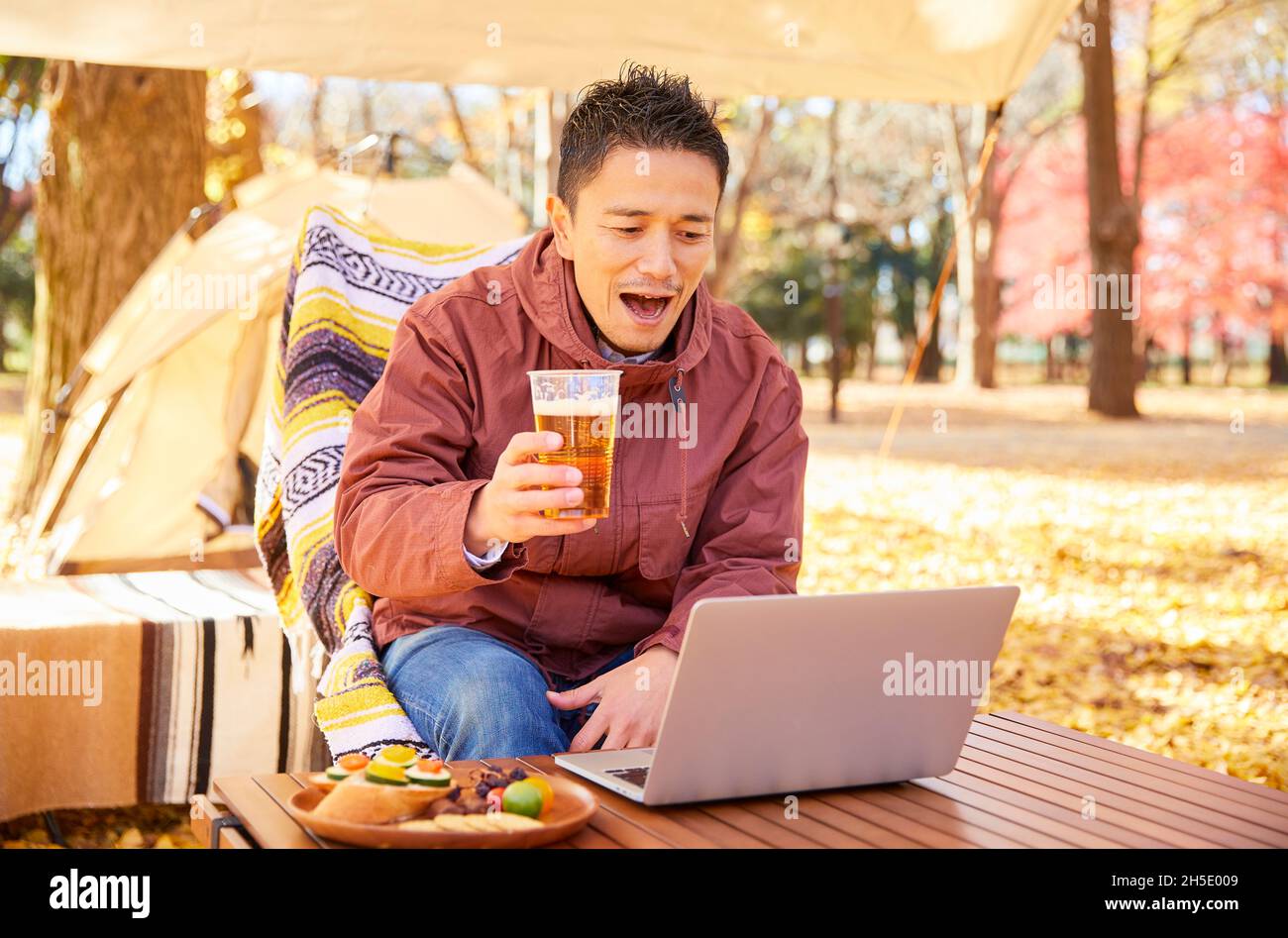 Homme japonais avec ordinateur portable au camping Banque D'Images