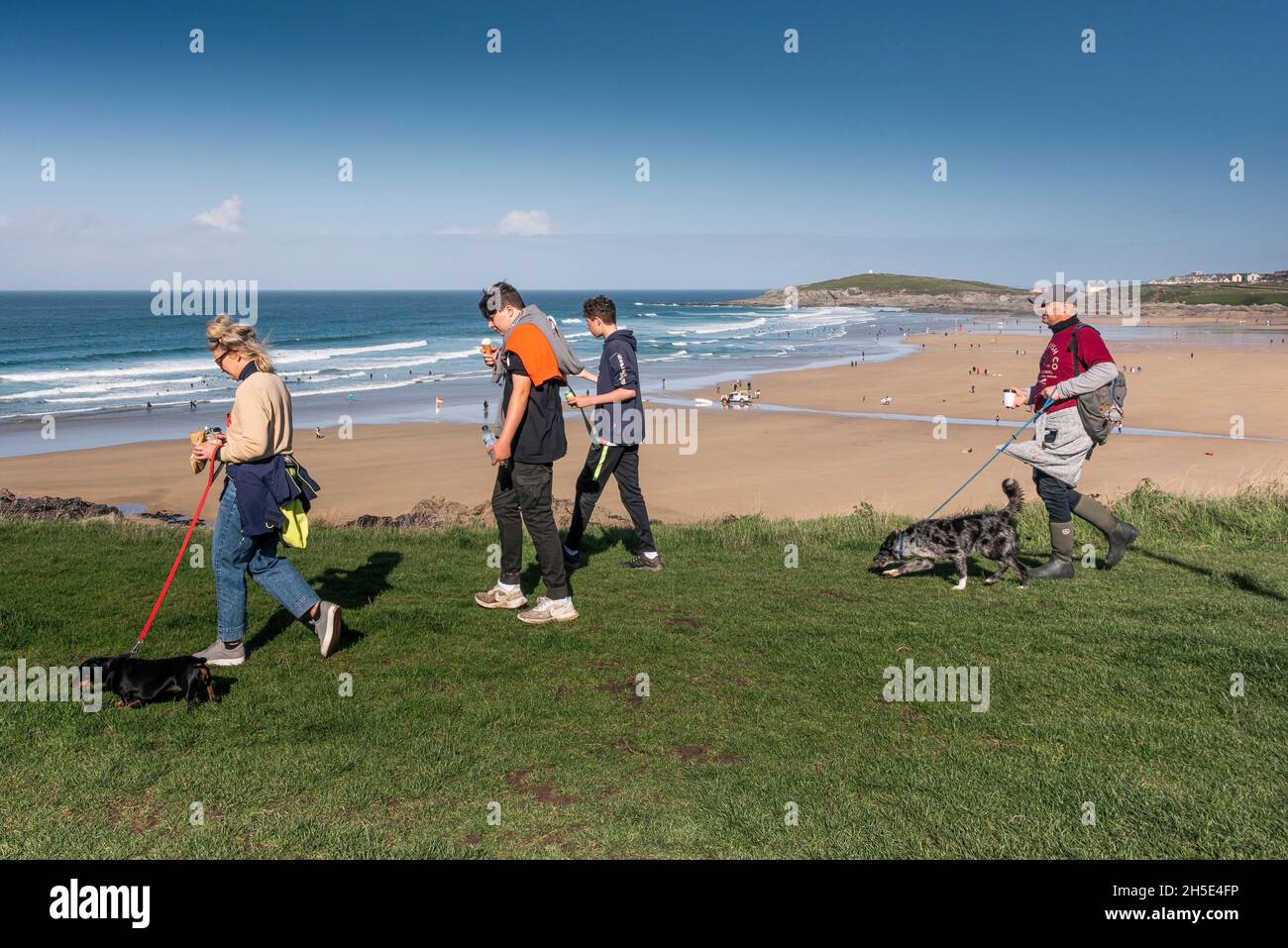 Une famille marchant leurs chiens le long de la côte surplombant la mer dans les Cornouailles. Banque D'Images