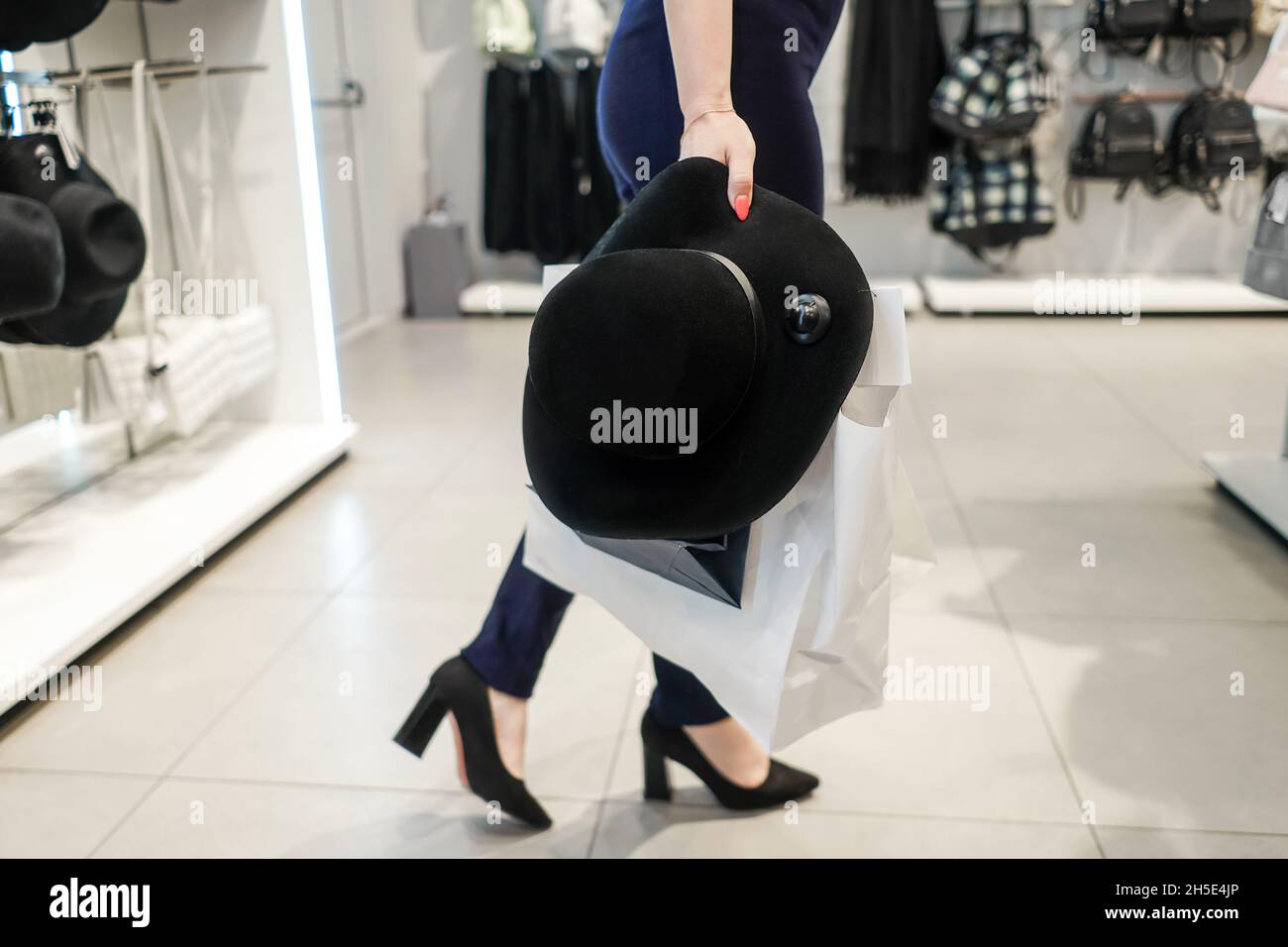 Femme avec sacs de shopping et chapeau noir dans hypermarché.Sans tête.Solde et concept du Vendredi fou. Banque D'Images