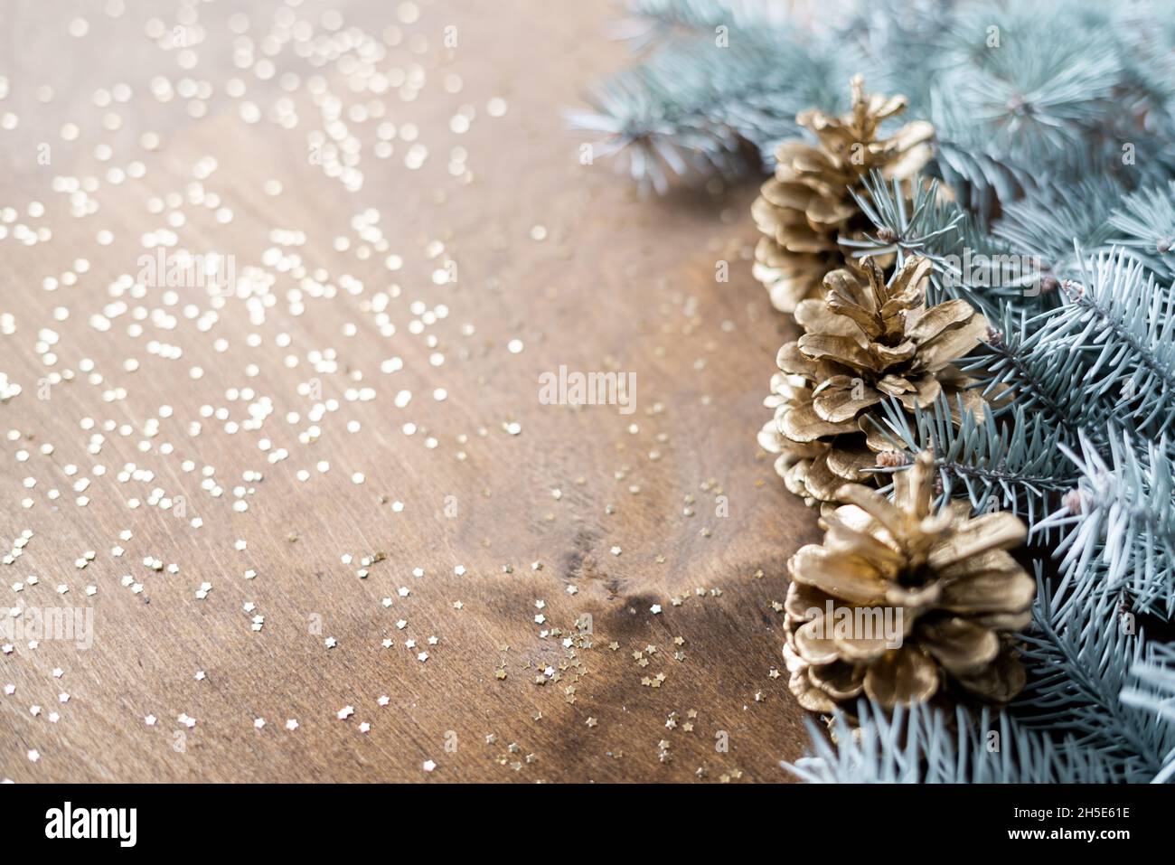 des cônes dorés naturels sur une table en bois avec des cornes d'or en forme d'étoiles, parmi des branches de sapin Banque D'Images