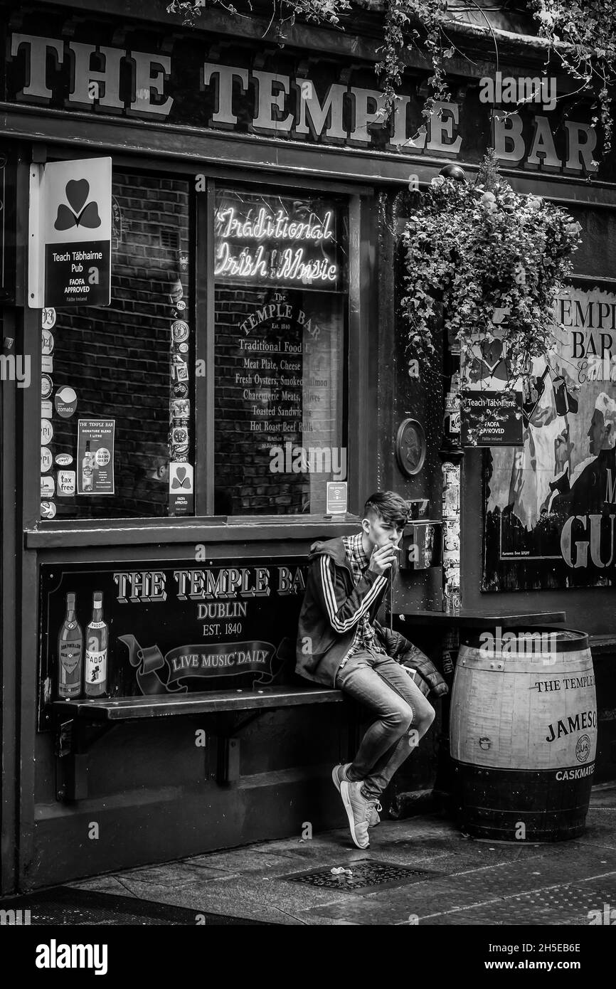 Un jeune homme fume une cigarette devant le célèbre Temple Bar Pub de Dublin Banque D'Images