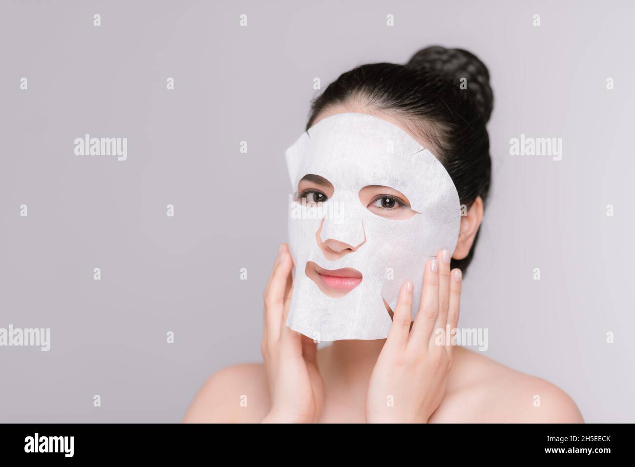 Belle femme asiatique l'application de la feuille de papier sur son visage masque fond blanc Banque D'Images
