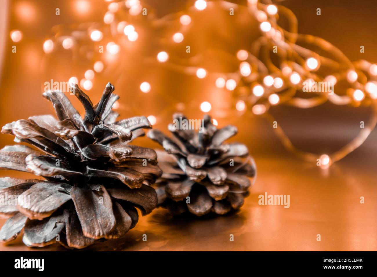 Cônes de Noël sur fond doré avec lumières.Arrière-plan de Noël. Banque D'Images