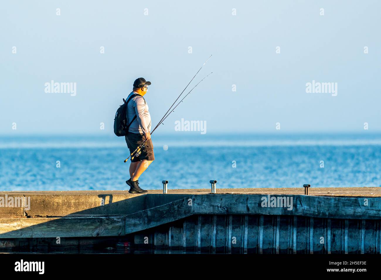 Un seul homme pêchant le long de la jetée au lever du soleil dans un parc local près d'Egg Harbor dans le comté de Door, Wisconsin. Banque D'Images