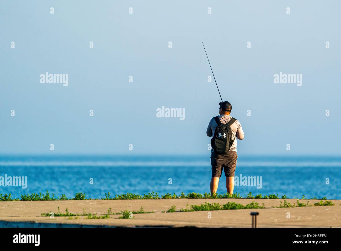 Un seul homme pêchant le long de la jetée au lever du soleil dans un parc local près d'Egg Harbor dans le comté de Door, Wisconsin. Banque D'Images