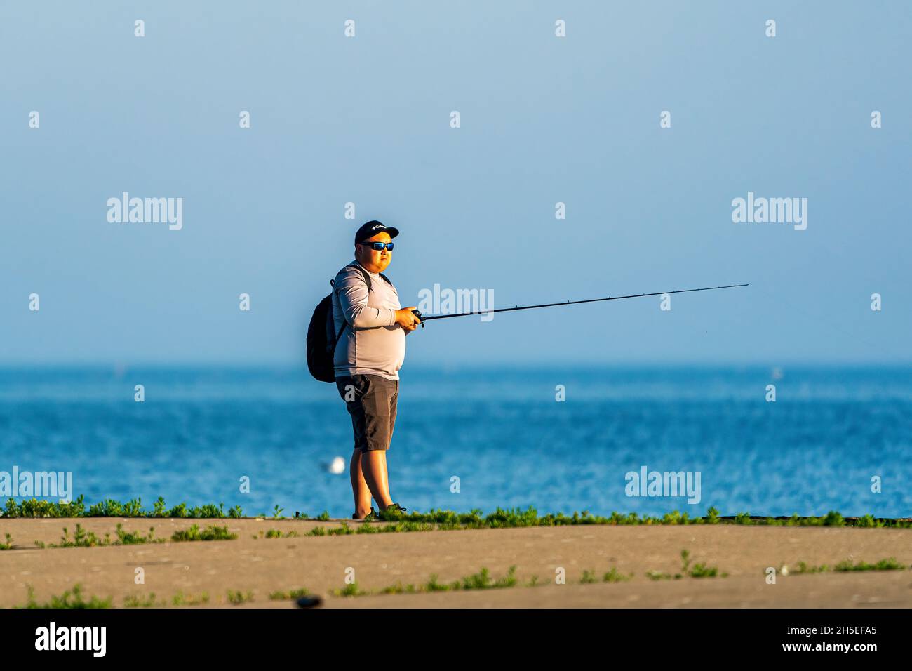 Un seul homme pêchant le long de la jetée au lever du soleil dans un parc local près d'Egg Harbor dans le comté de Door, Wisconsin. Banque D'Images