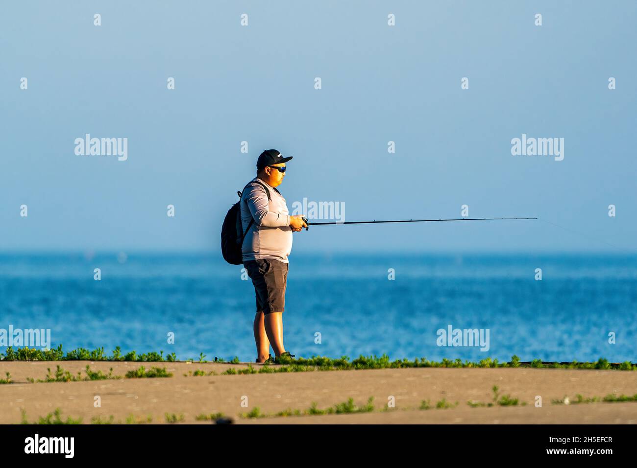 Un seul homme pêchant le long de la jetée au lever du soleil dans un parc local près d'Egg Harbor dans le comté de Door, Wisconsin. Banque D'Images
