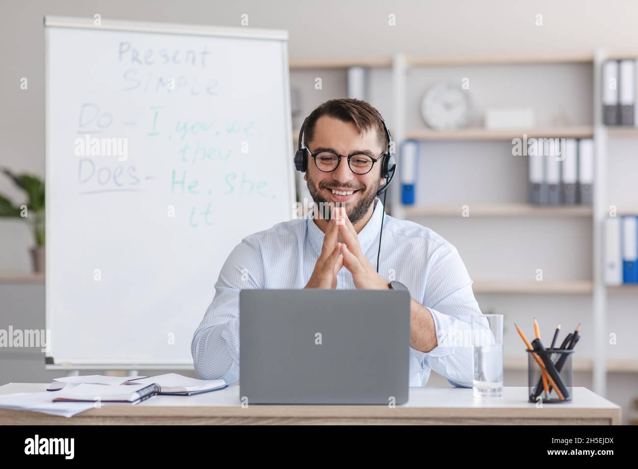 Joyeux homme caucasien mature professeur dans des lunettes avec tableau avec des règles, des gestes, regarde l'ordinateur portable Banque D'Images