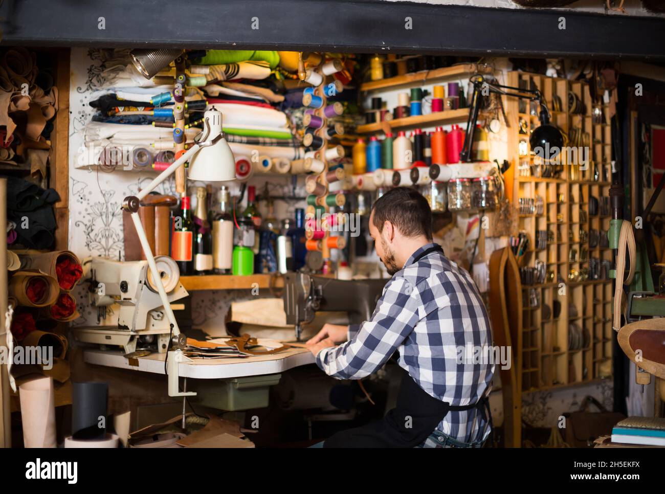 homme travailleur couture de points sur la ceinture dans un atelier de cuir Banque D'Images
