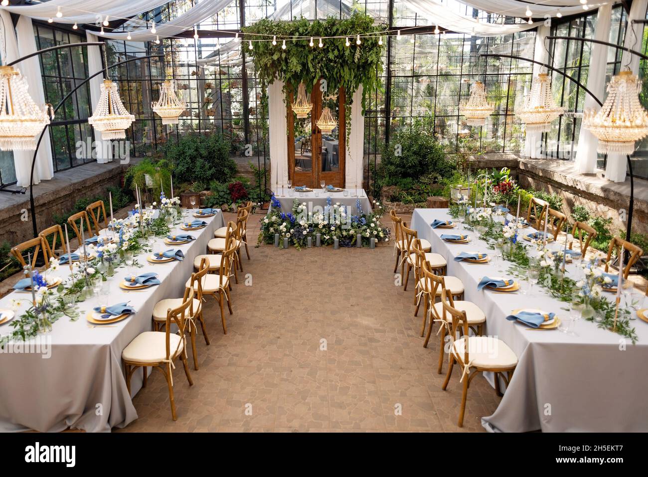 Salle de banquet de mariage dans la serre, les tables sont disposées,  décorées avec des fleurs fraîches, des bougies, des lustres en cristal.Mise  au point sélective douce Photo Stock - Alamy