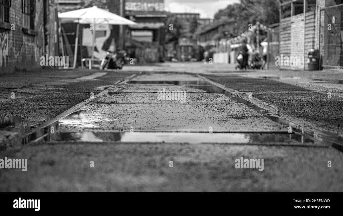 voies de route à travers l'asphalte dans une rue de berlin représentée en noir et blanc. texture et détail dans une humeur terne Banque D'Images