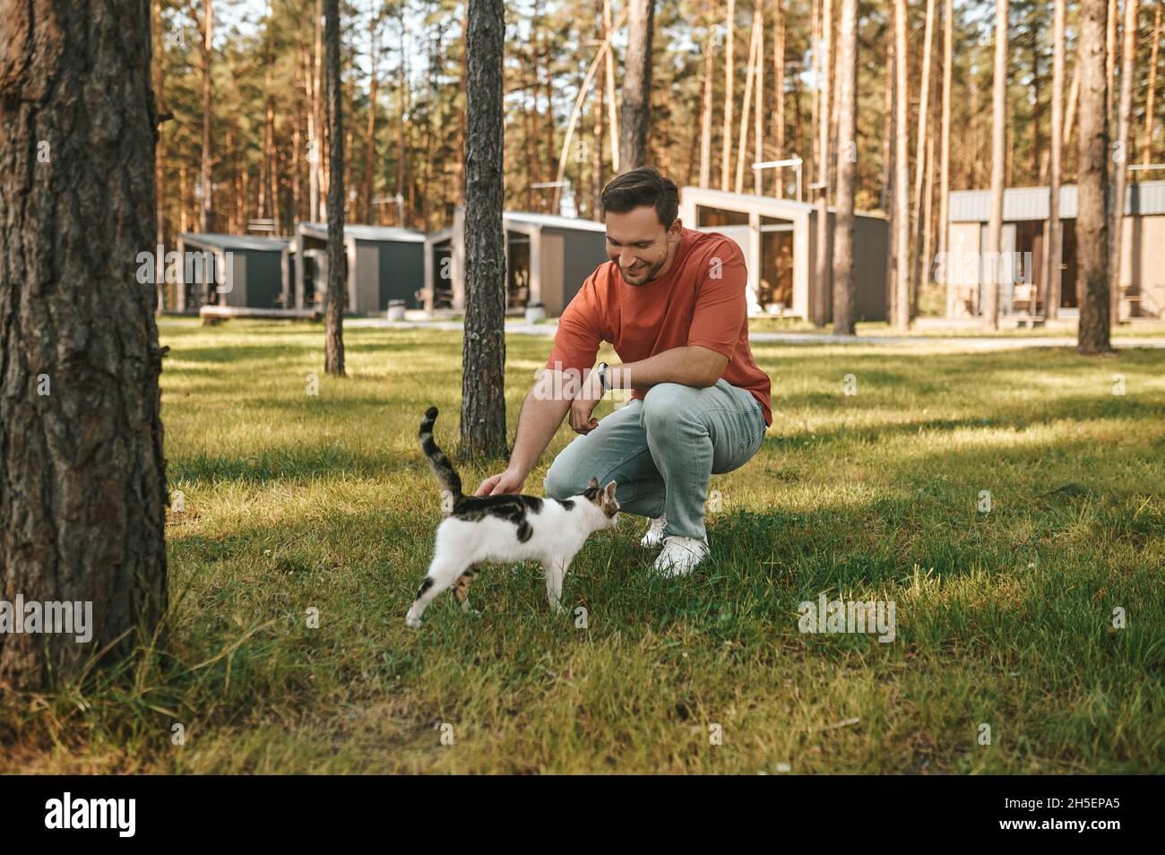 Homme qui croque sur la pelouse en touchant le chat Banque D'Images