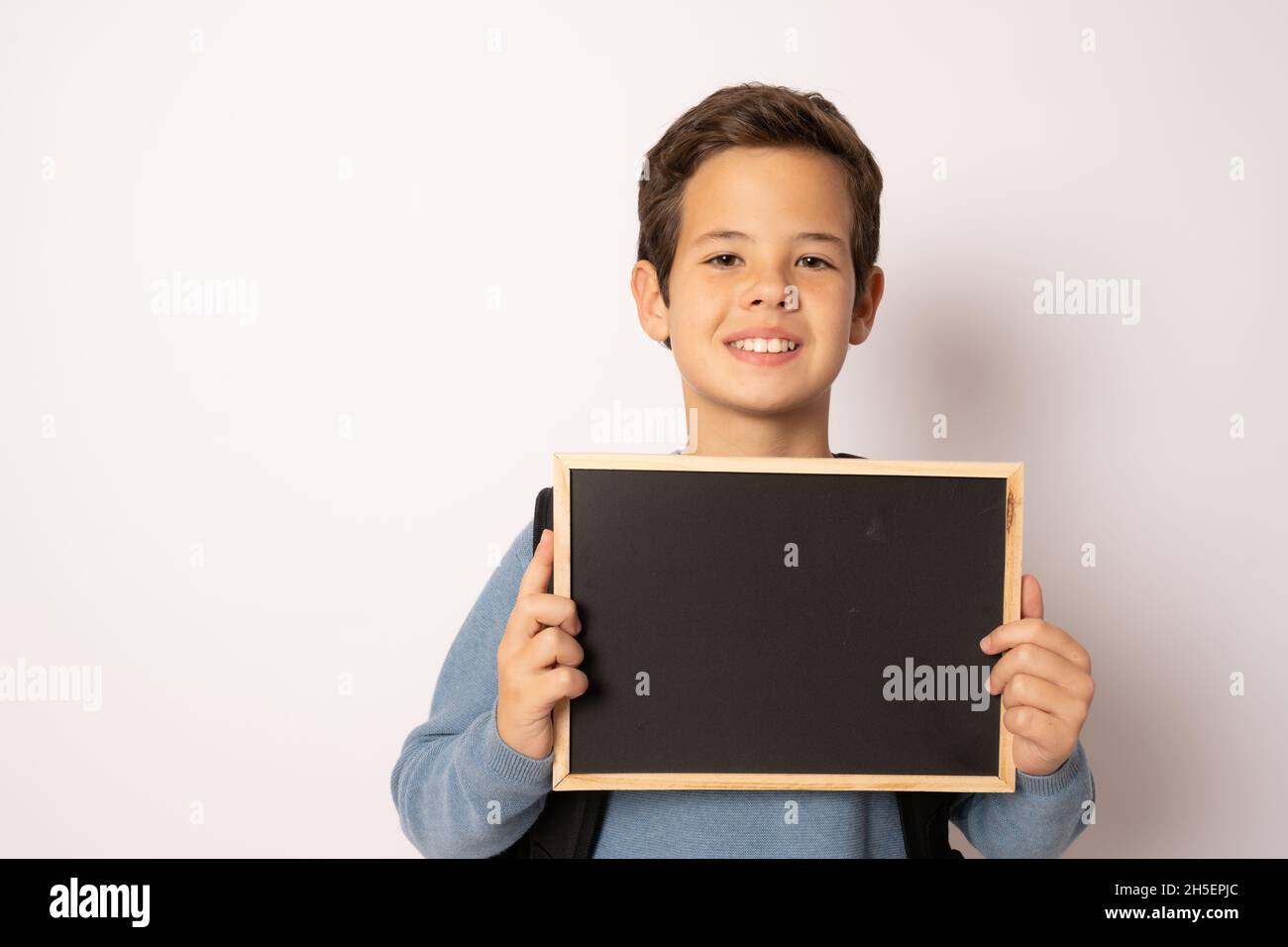 Garçon d'école tenant un tableau de craie isolé sur fond blanc Banque D'Images