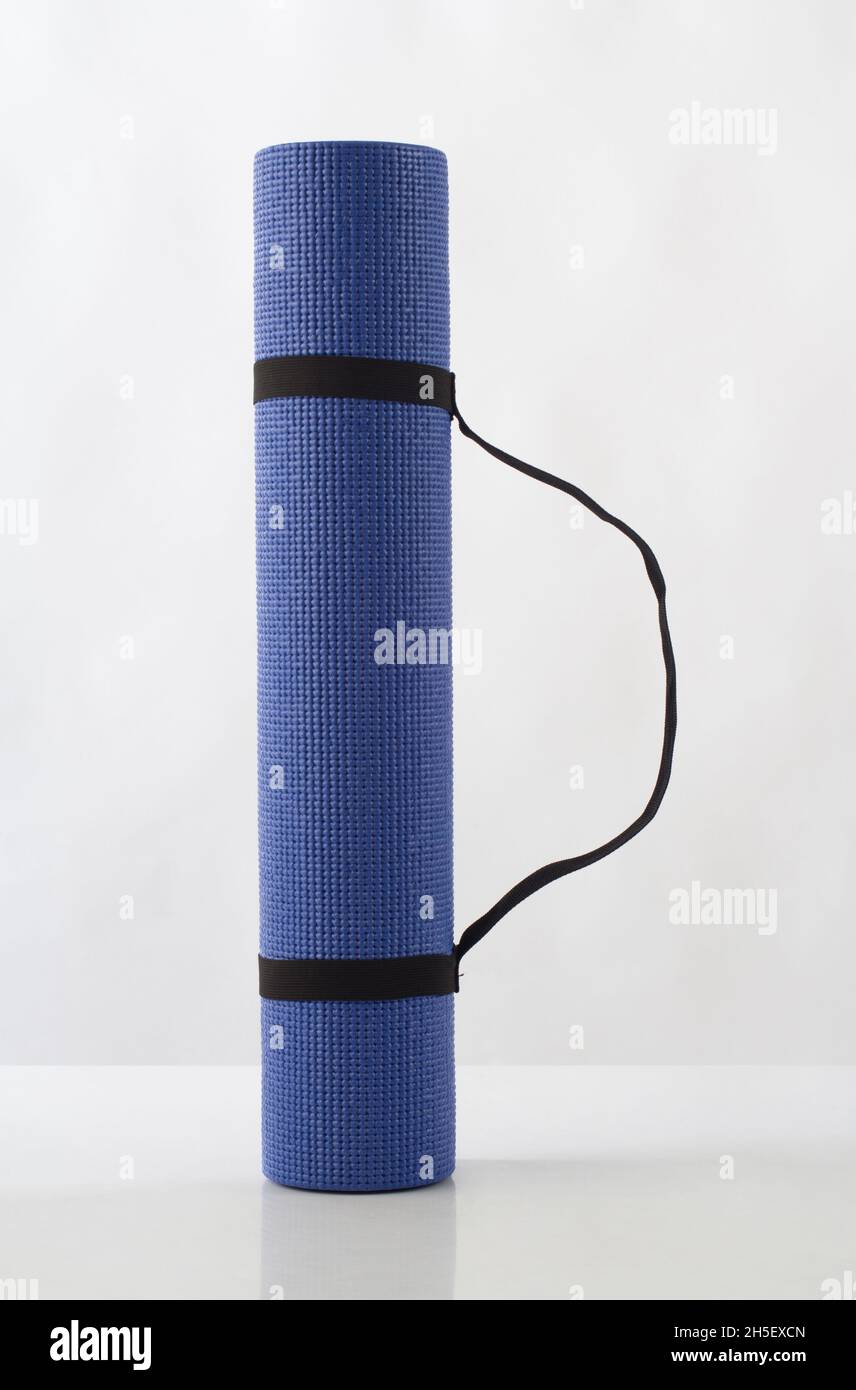 Tapis de yoga bleu enroulé isolé sur fond blanc Banque D'Images
